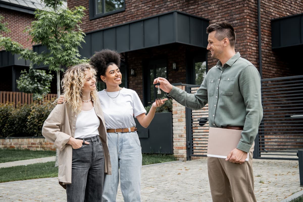 A real estate agent handing house keys to happy new homeowners.